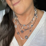 Model wears several happy flowers necklaces in varying colors