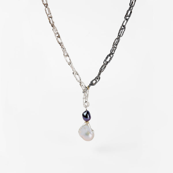 A large white freshwater pearl dsngles at the end of a handcrafted ombre Sterling silver chain forming a sliding lariat