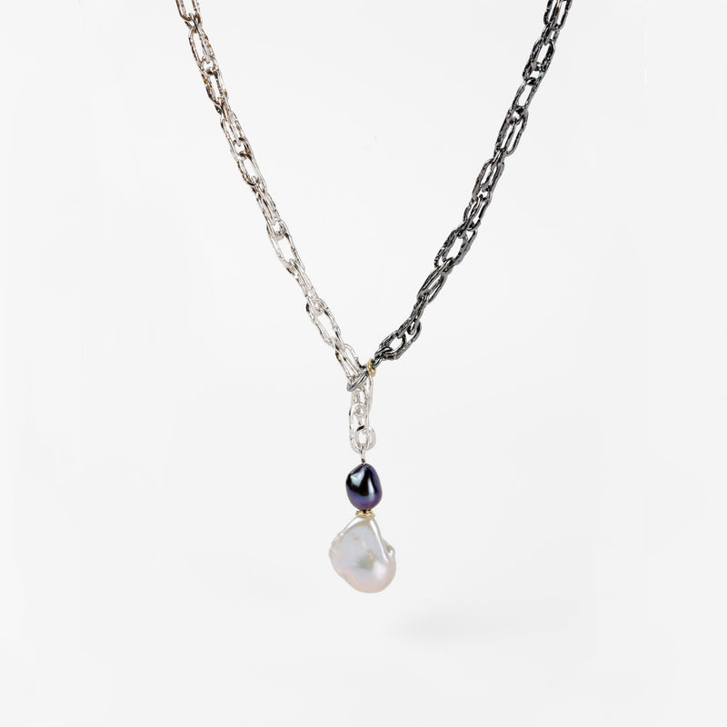 A large white freshwater pearl dsngles at the end of a handcrafted ombre Sterling silver chain forming a sliding lariat