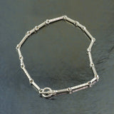 Textured Sterling silver stick links in varying lengths form this necklace with a toggle lock