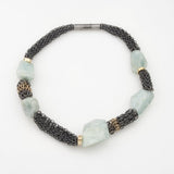 Large aquamarine chunks are strung in between sections of oxidized Sterling Silver chain mail accented with 18KY gold links.