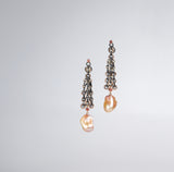 Long earrings in oxidized (black) silver with a giant peach colored oblong pearl at the bottom. colored gold accents and colored diamonds are also included.