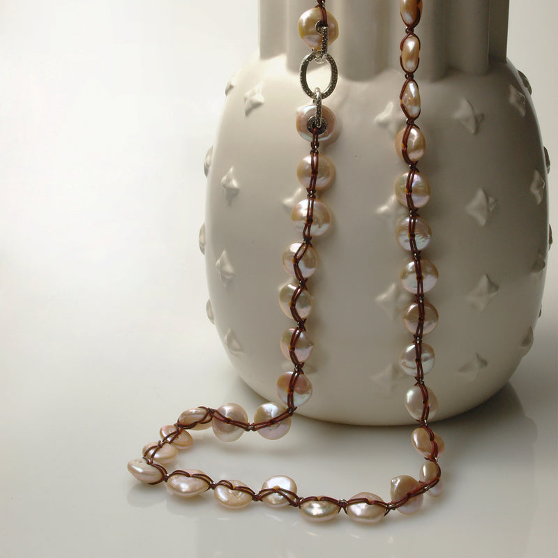 pink button pearl necklace is draped of a vase