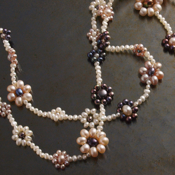 detail of the LEI happy flowers freshwater pearl necklace against a dark background
