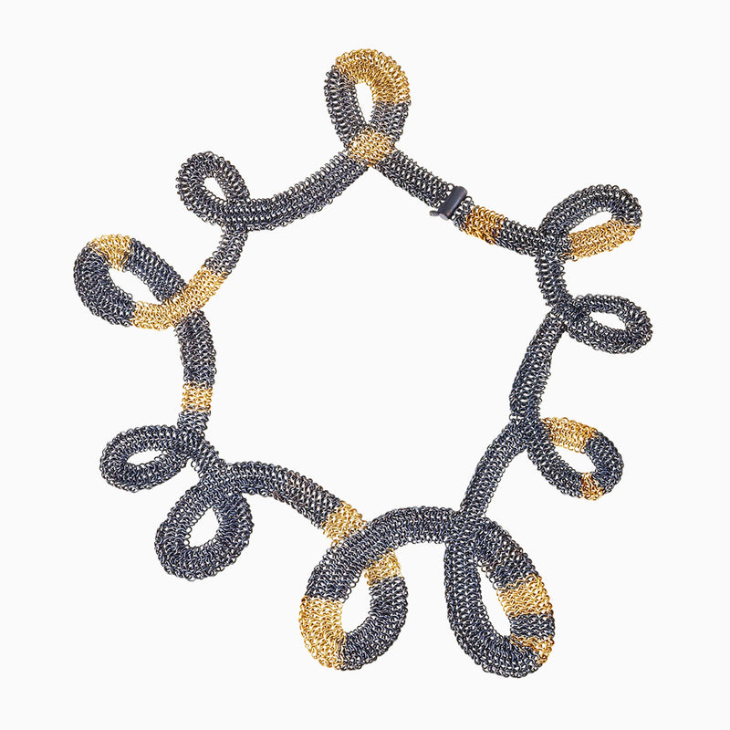 The whole SERPENTINE necklace is shown against a white background. This necklace is woven of hundreds of tiny Oxidized Sterling silver and 18KY gold rings with a tiny barrel clasp showing.